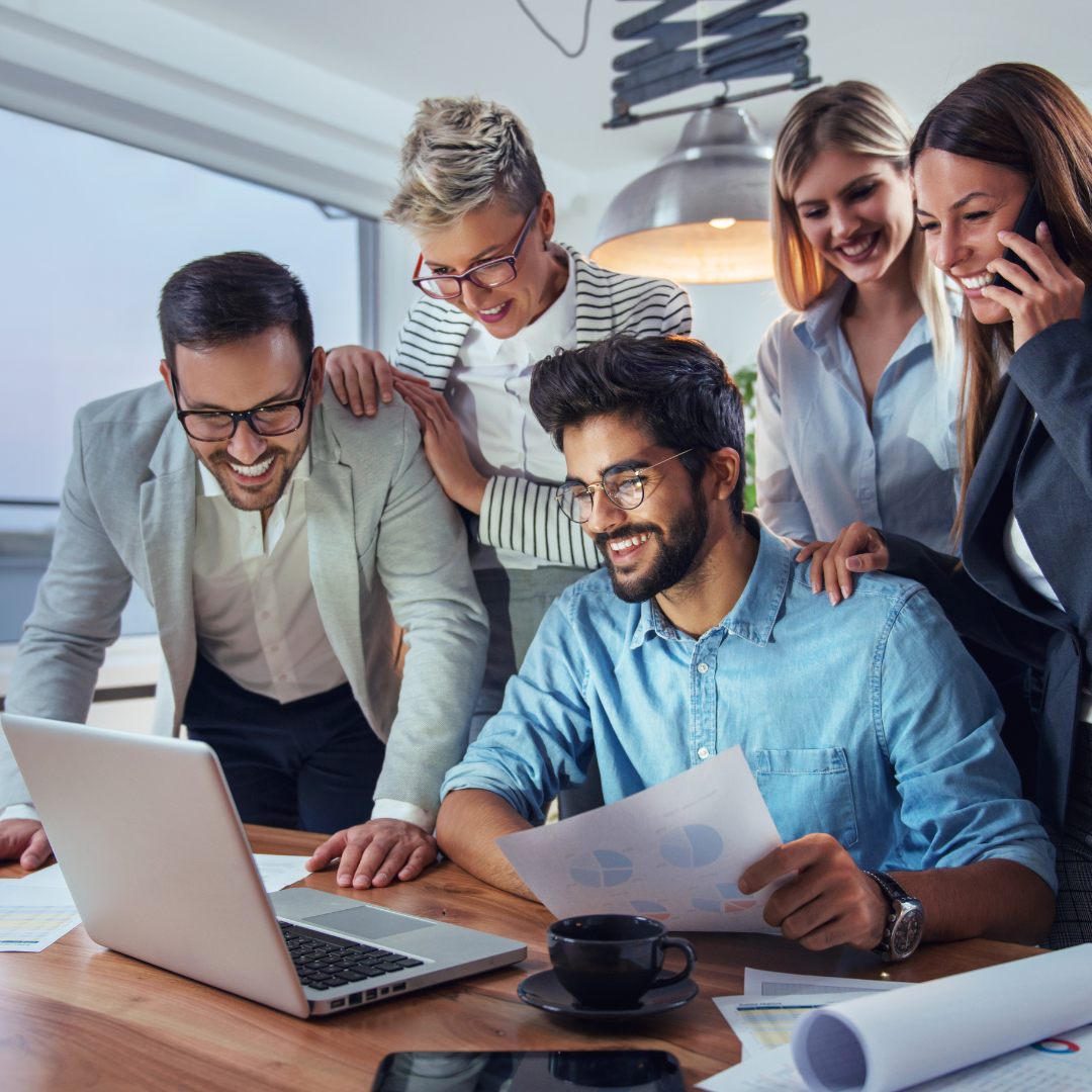 Five smiling business people around a computer.